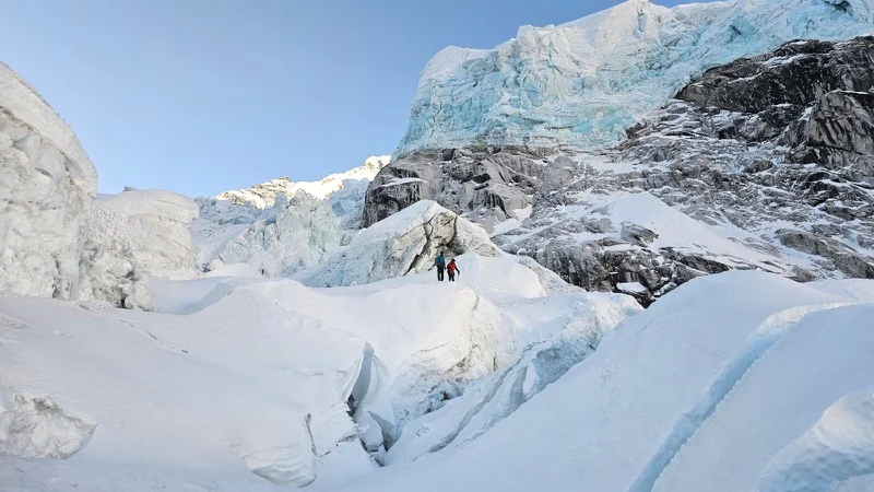 Two figures among the seracs of the Khumbu Icefall, at first light